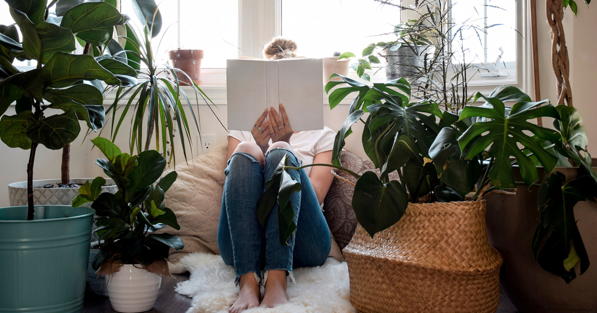 Frau sitzt in einer Kuschelecke und liest | Credit: iStock.com/JulieAlexK