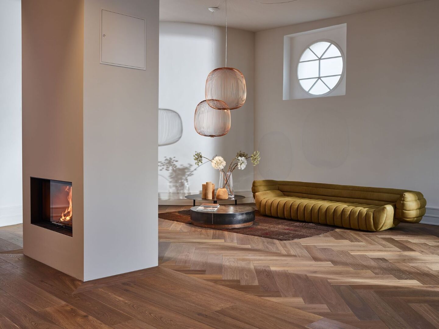 Wohnzimmer mit Couch, Kamin und Walfischgrät-Boden