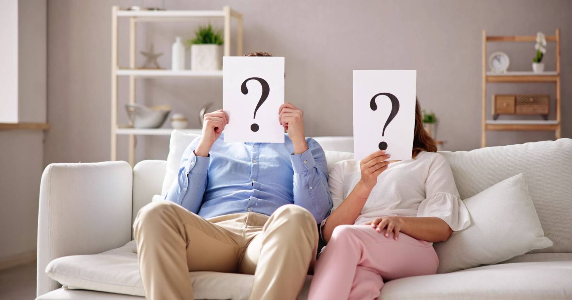 Paar mit Fragezeichenschildern über dem Kopf bei der Beantwortung der 36 Fragen von Arthur Aron