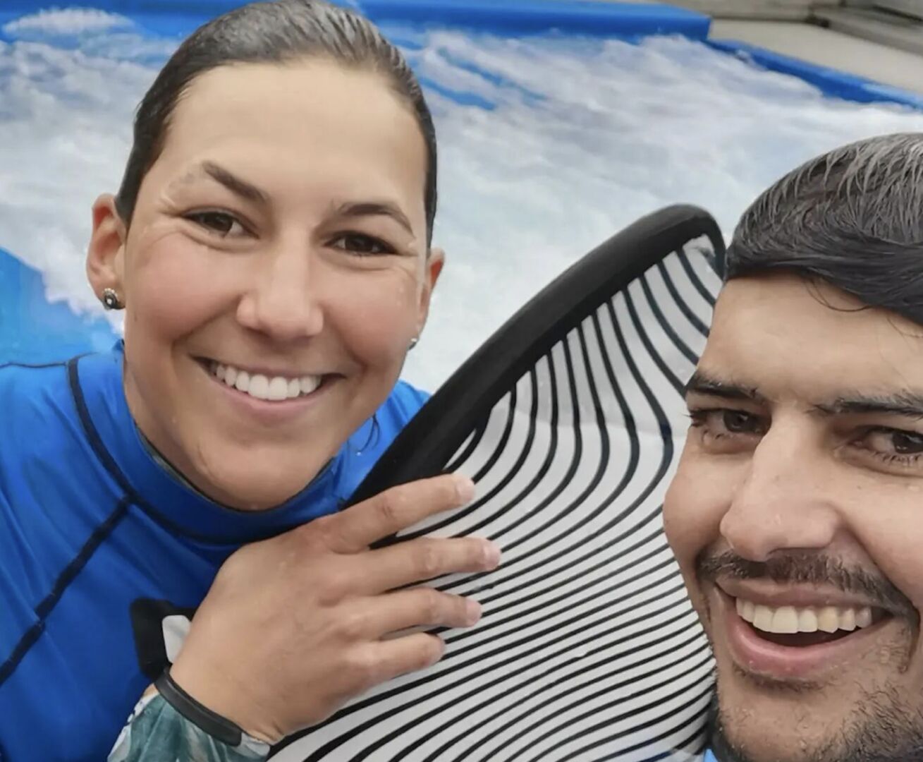 Porträt vor künstlicher Surfwelle, beide lachen