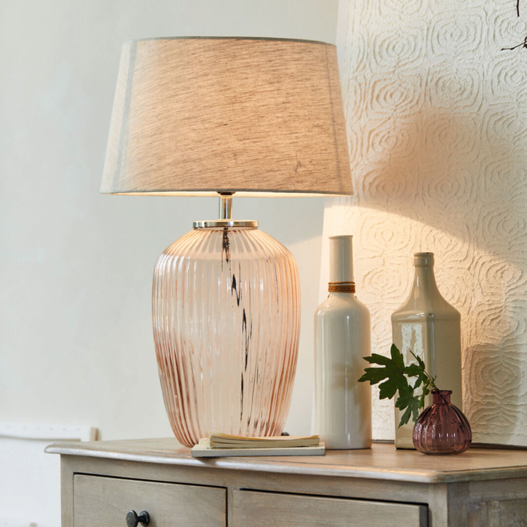 Stehlampe in zartem Rosa vor weißer Wand