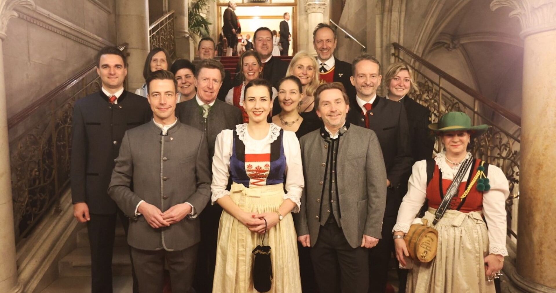 16 Menschen in Tracht auf Stufen zum Wiener Rathaus