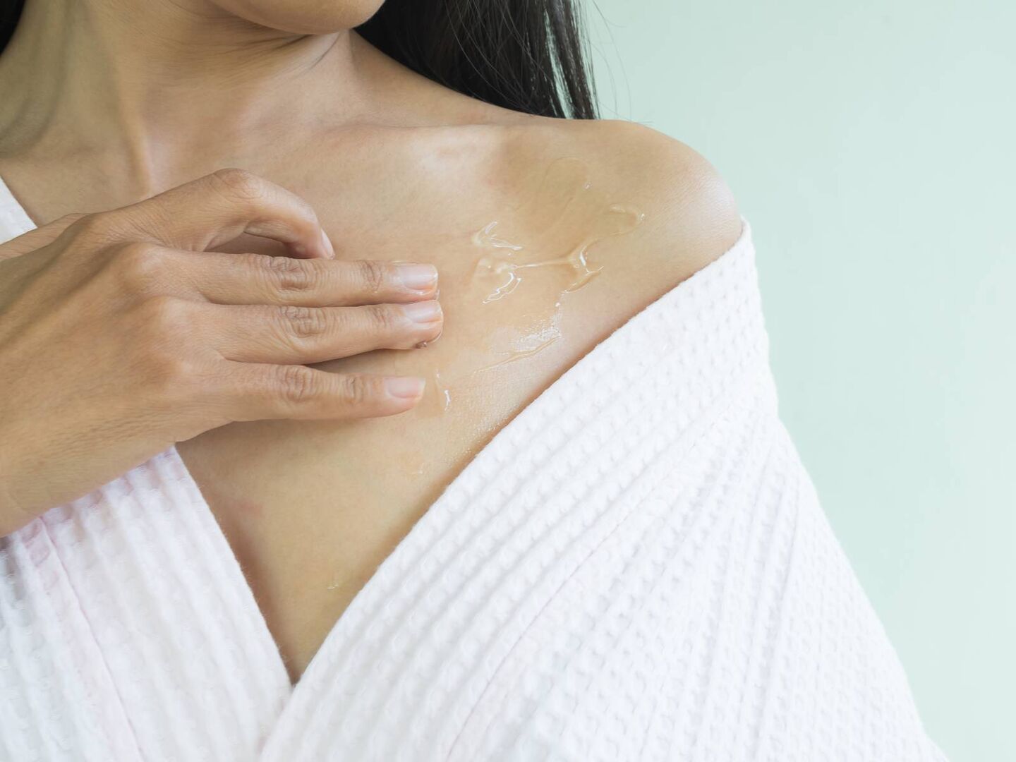 Frau cremt sich Schlüsselbein mit Aloe-Vera-Gel ein