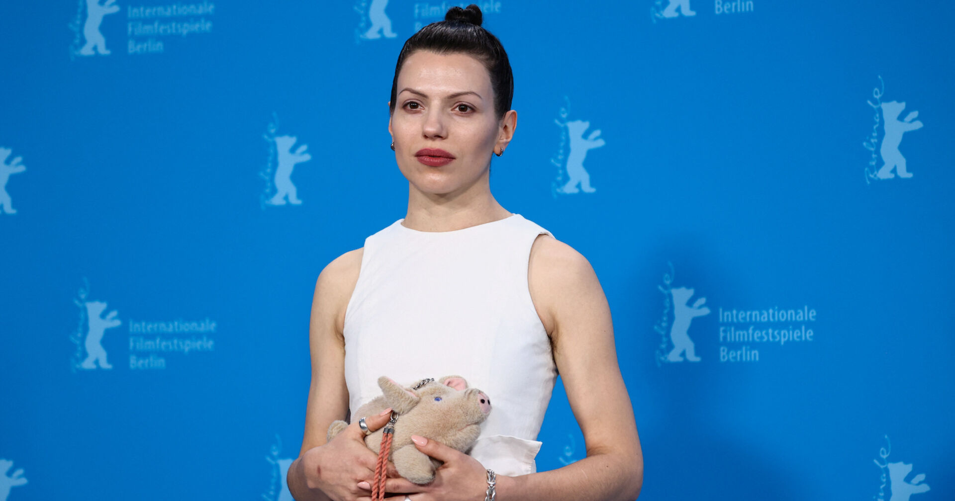 Anja Plaschg bei der Berlinale mit einem Stoffschwein in der Hand und einem weißen Kleid.