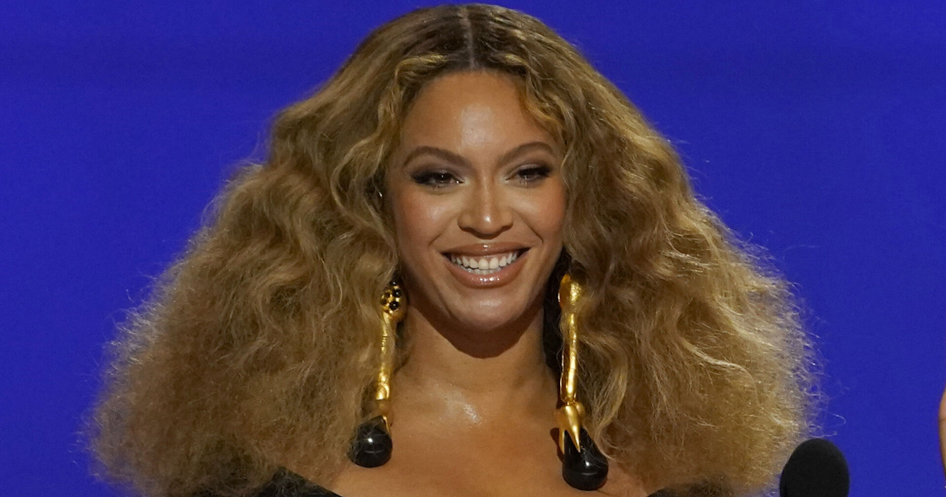 Beyoncé mit offenen, voluminösen Haaren auf einer Tribüne.