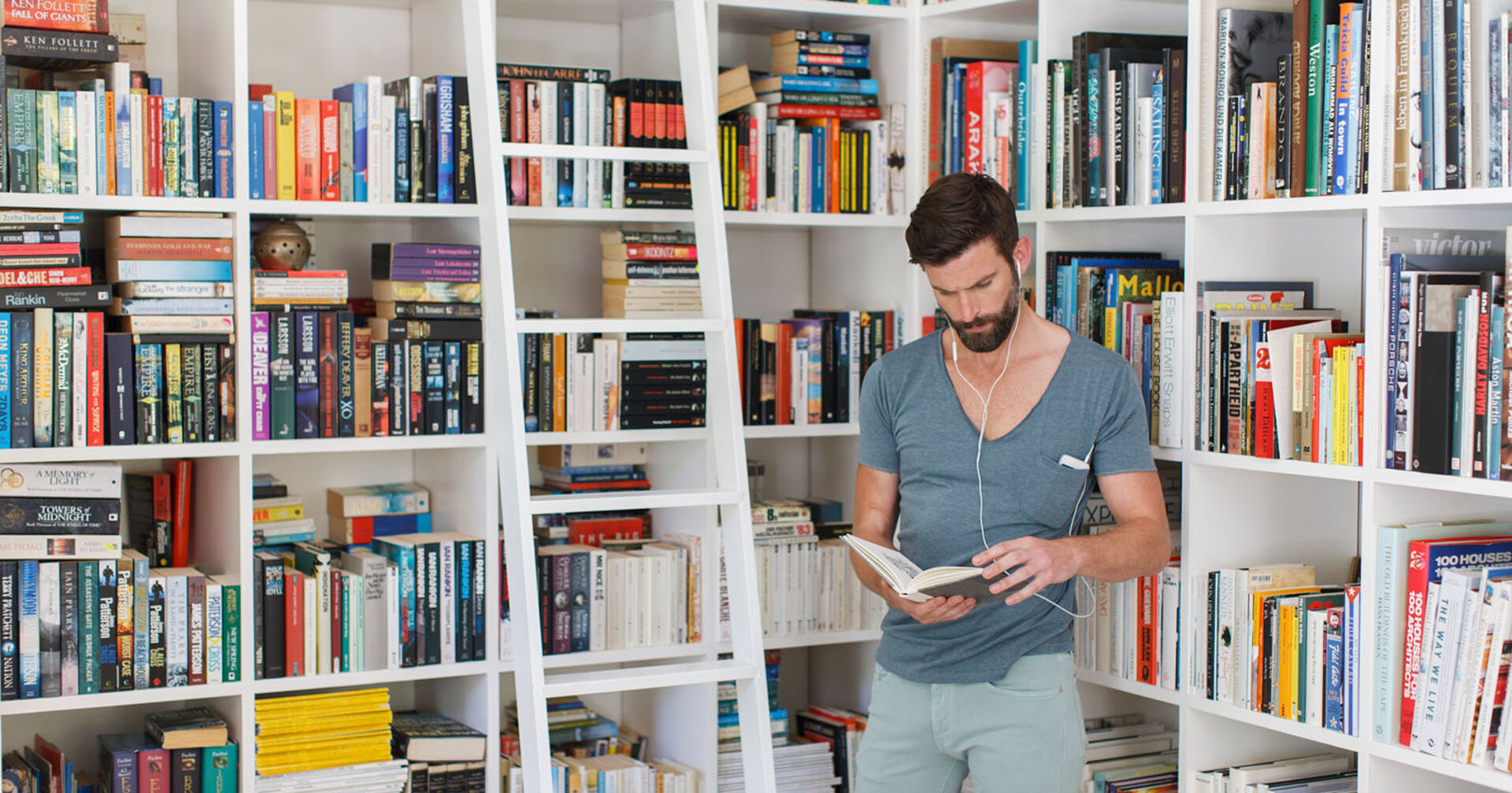 Mann steht bei seinen Bücherregalen | Credit: iStock.com/Astronaut Images