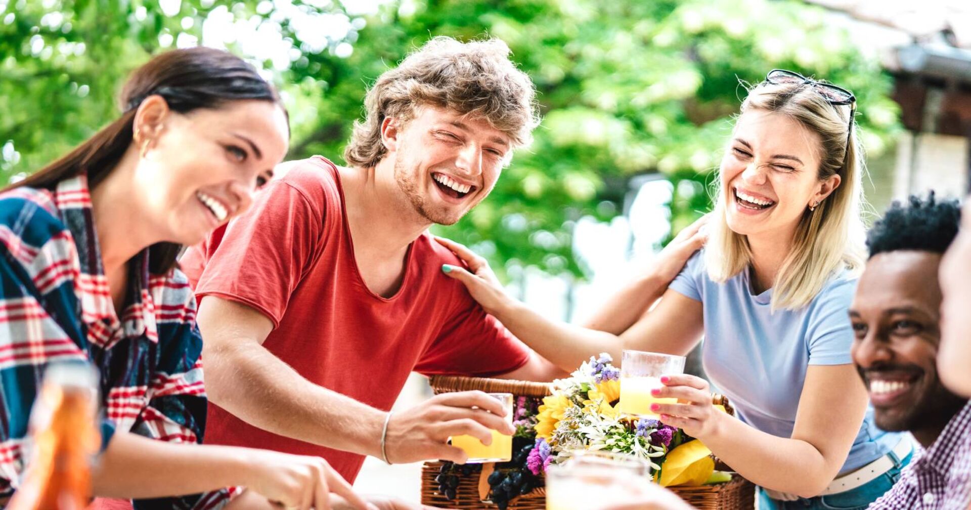 4 Freunde, die zusammen am Tisch sitzen und lachen.