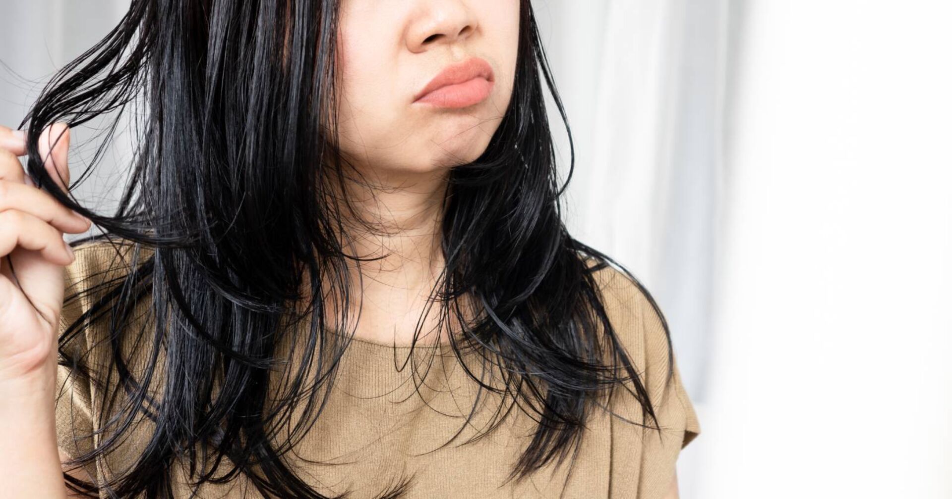 Frau mit fettigen Haaren mit einem unglücklichen Gesichtsausdruck, die in den Spiegel blickt