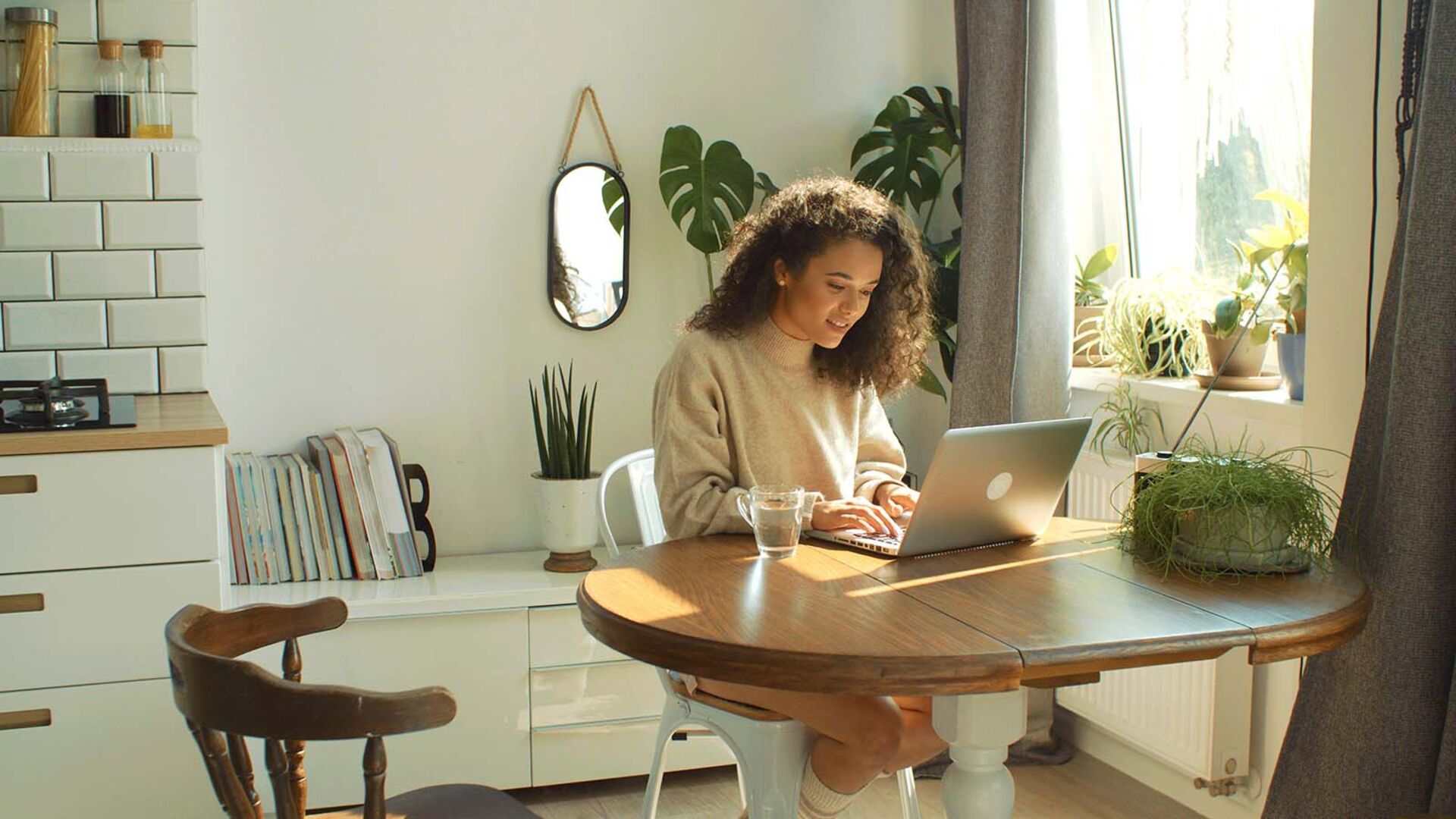 Frau sitzt mit Laptop in der Küche | Credit: iStock.com/TheRabbitHolePictures