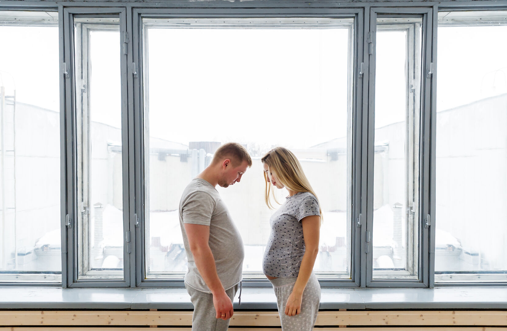 Mann und Frau mit Schwangerschaftsbauch sehen sich an