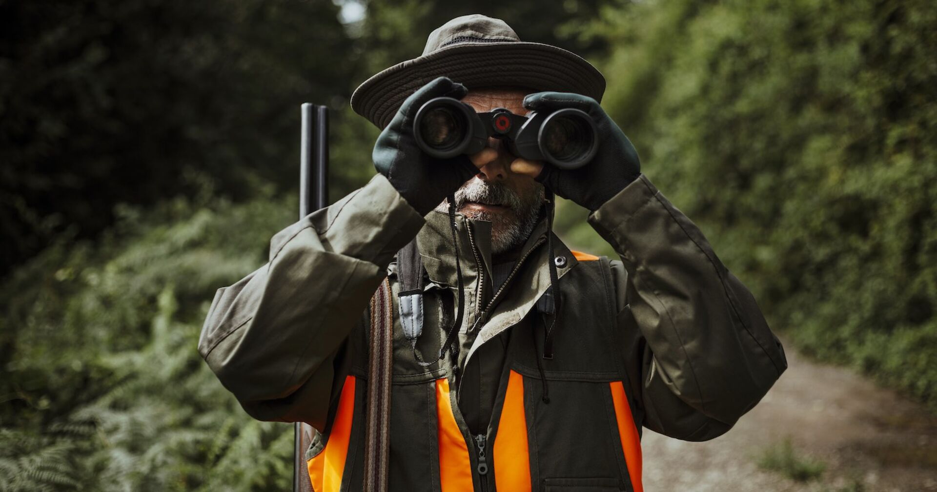 Ein Jäger mit Fernglas-Gucker unterwegs im Wald.