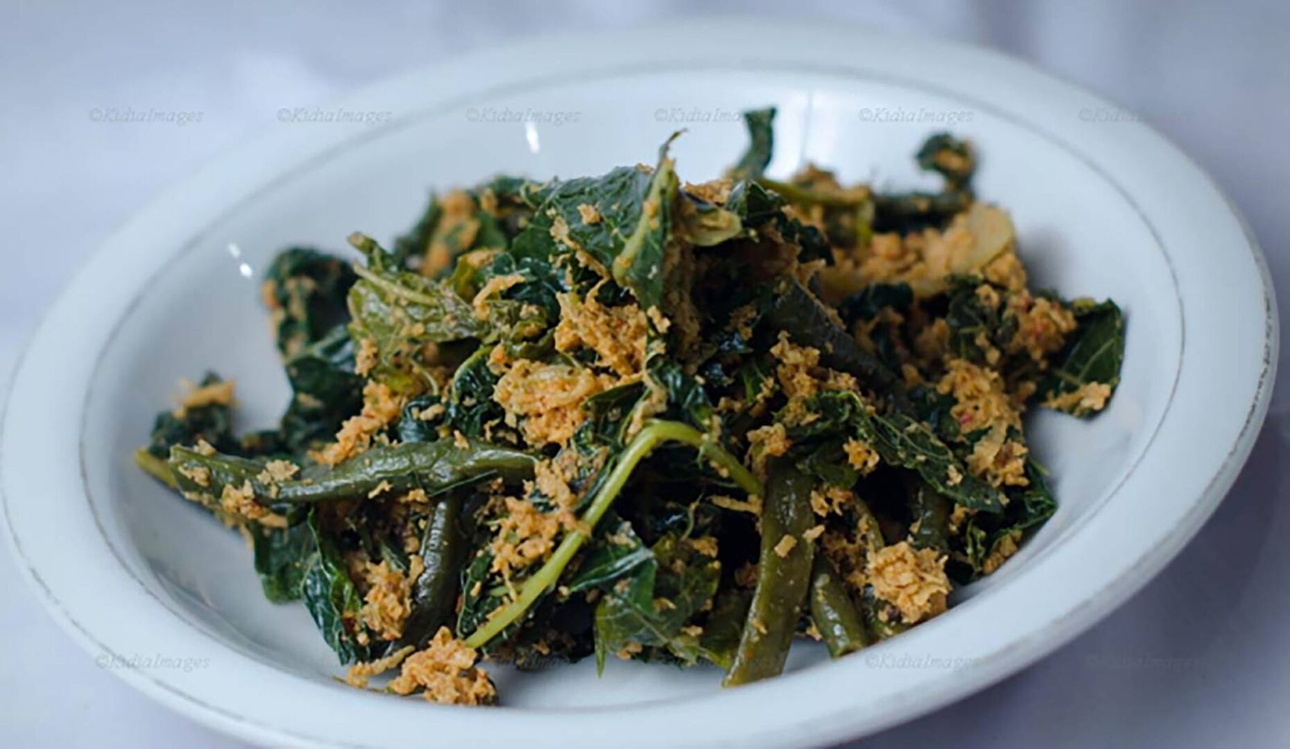 Teller mit gebratenen Karfiol- und Brokkoliblättern, garniert mit geriebenen Knoblauch