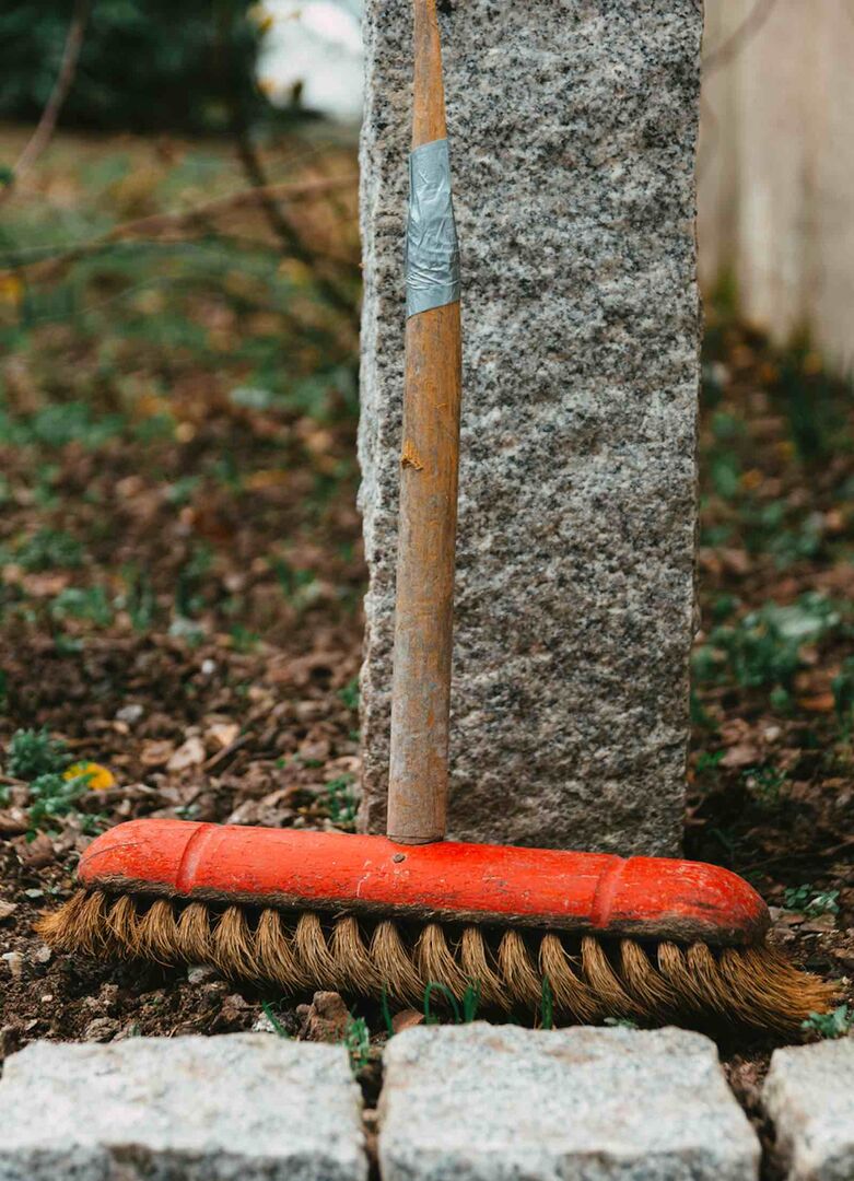 Ein alter Besen lehnt an einer Mauer.