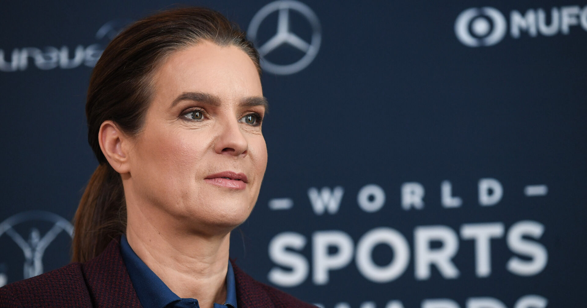 Katharina Witt vor einer Fotoleinwand mit geschlossenen Haaren.