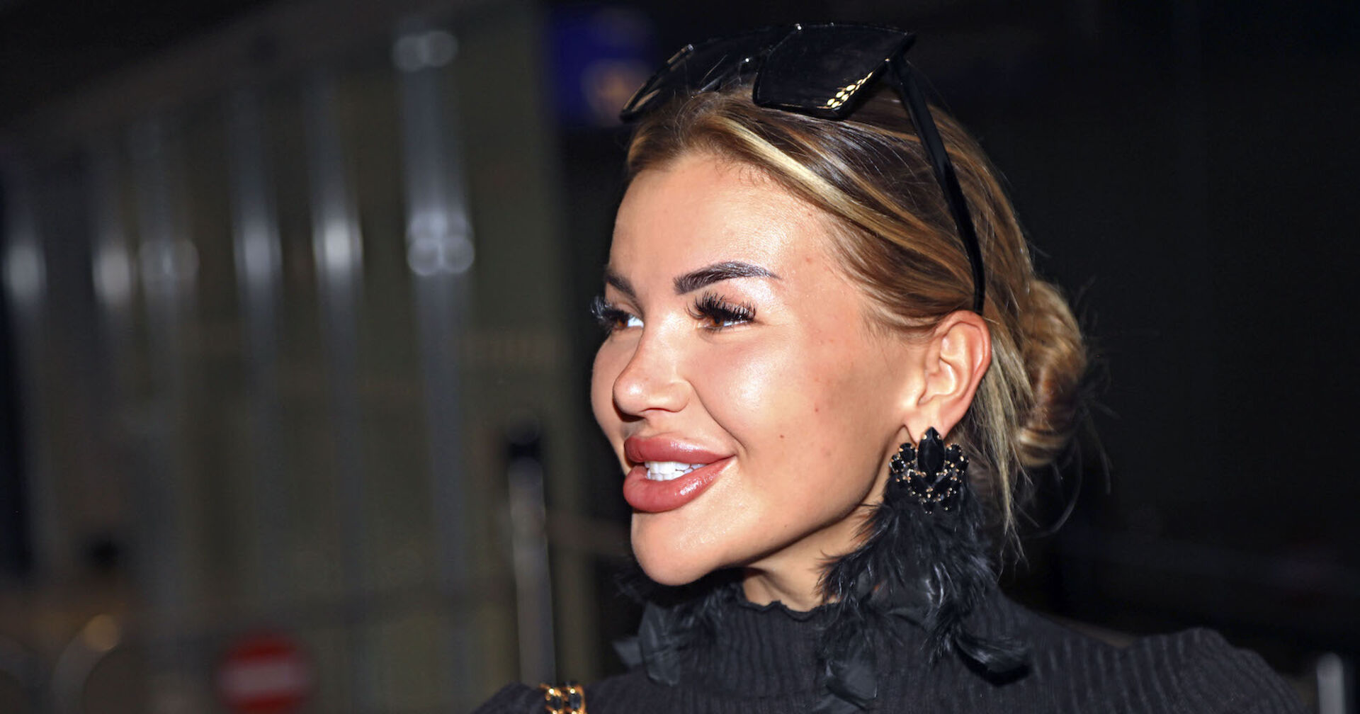 Kim Virginia mit zusammen gebundenen Haaren, einer Sonnenbrille und einem schwarzen Pullover.