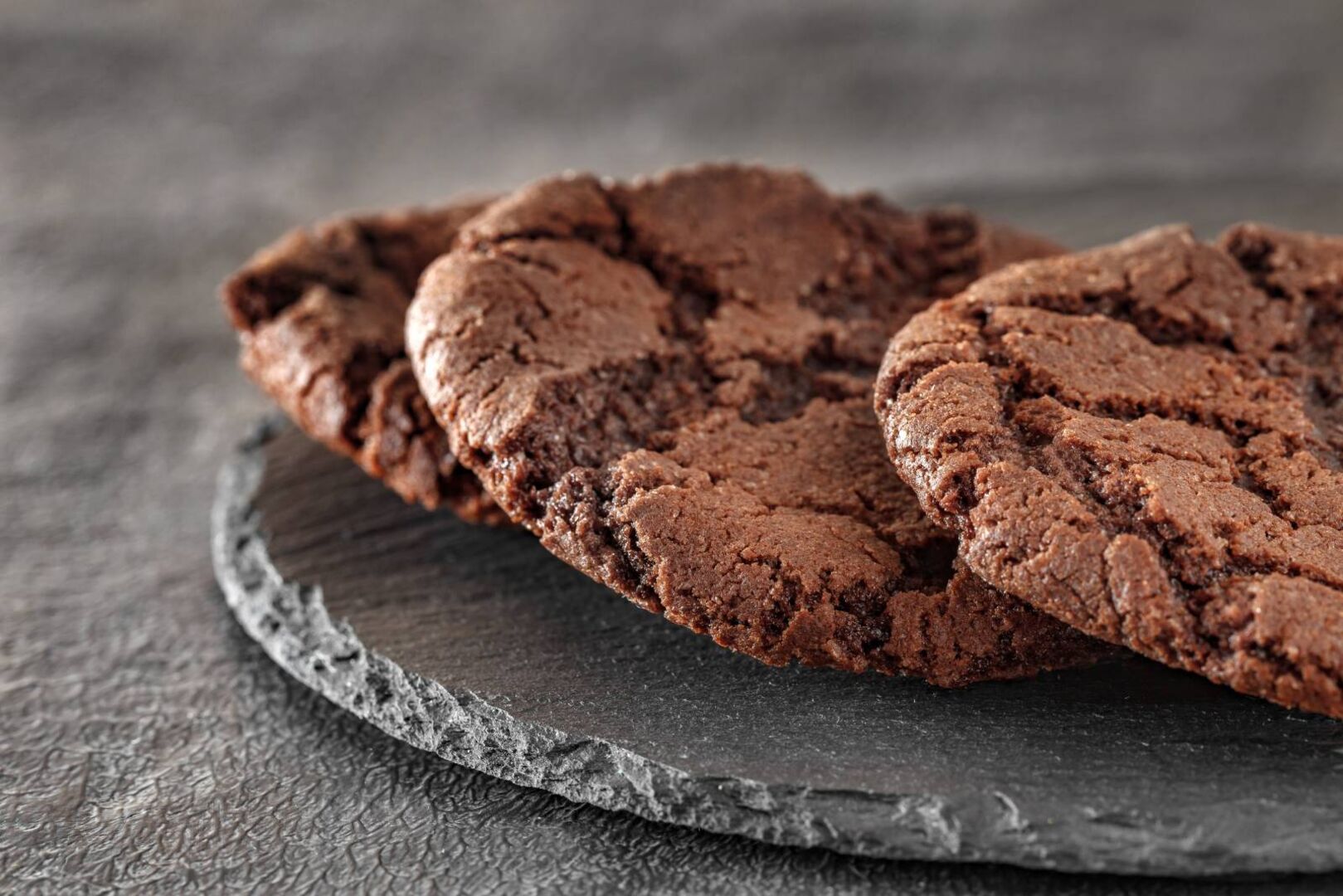3 Stück Nutellakekse serviert auf einer grauen Schieferplatte