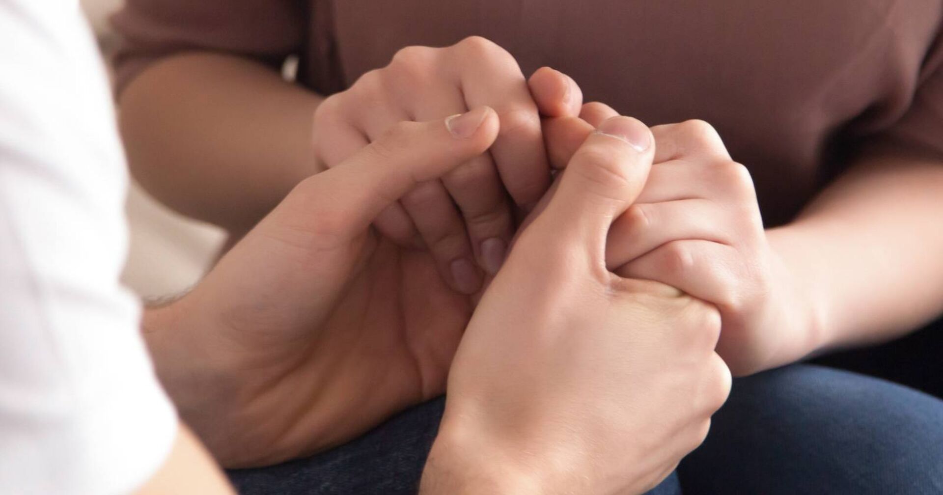 Close-Up eines Pärchens, welches gemeinsam Händchen hält.