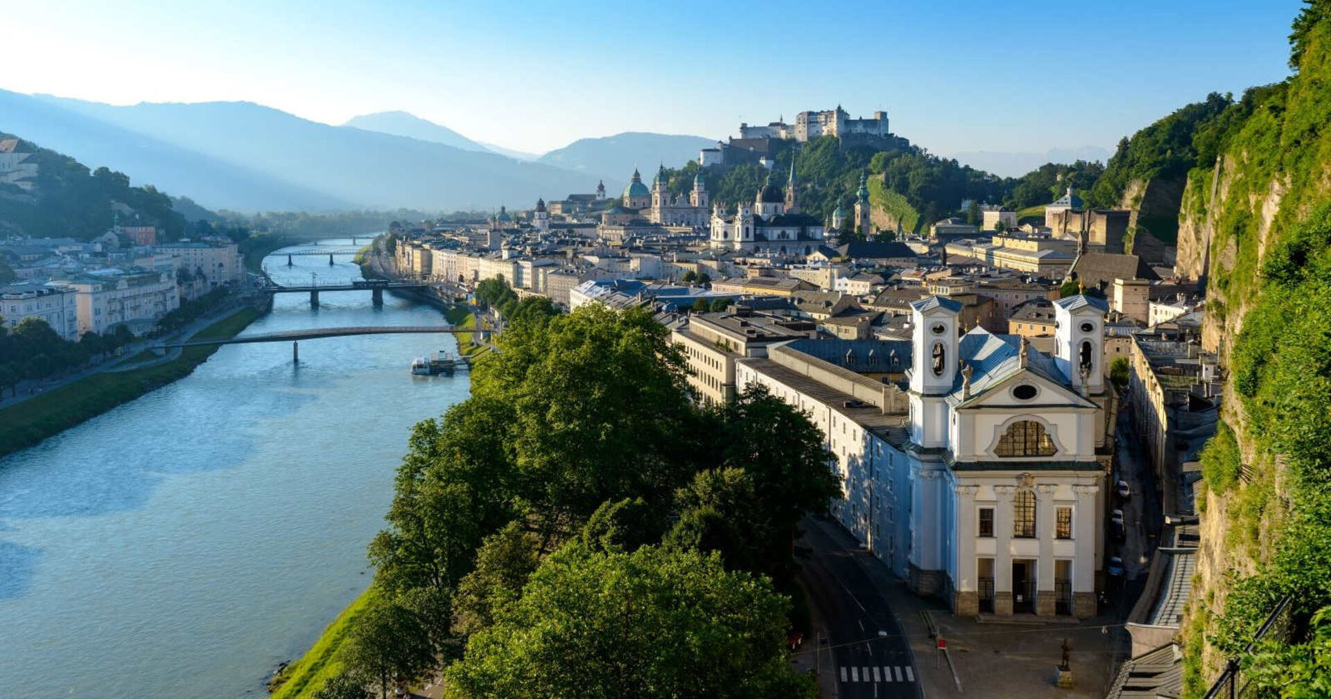 Die Stadt Salzburg mit Blick auf die Salzach und die Festung bei Sonnenaufgang.