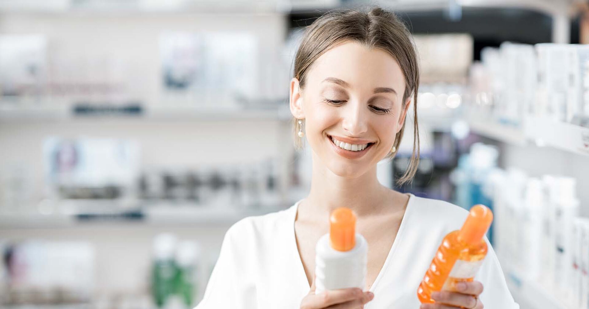 Frau mit Sonnencreme-Flaschen in der Hand | Credit: iStock.com/RossHelen