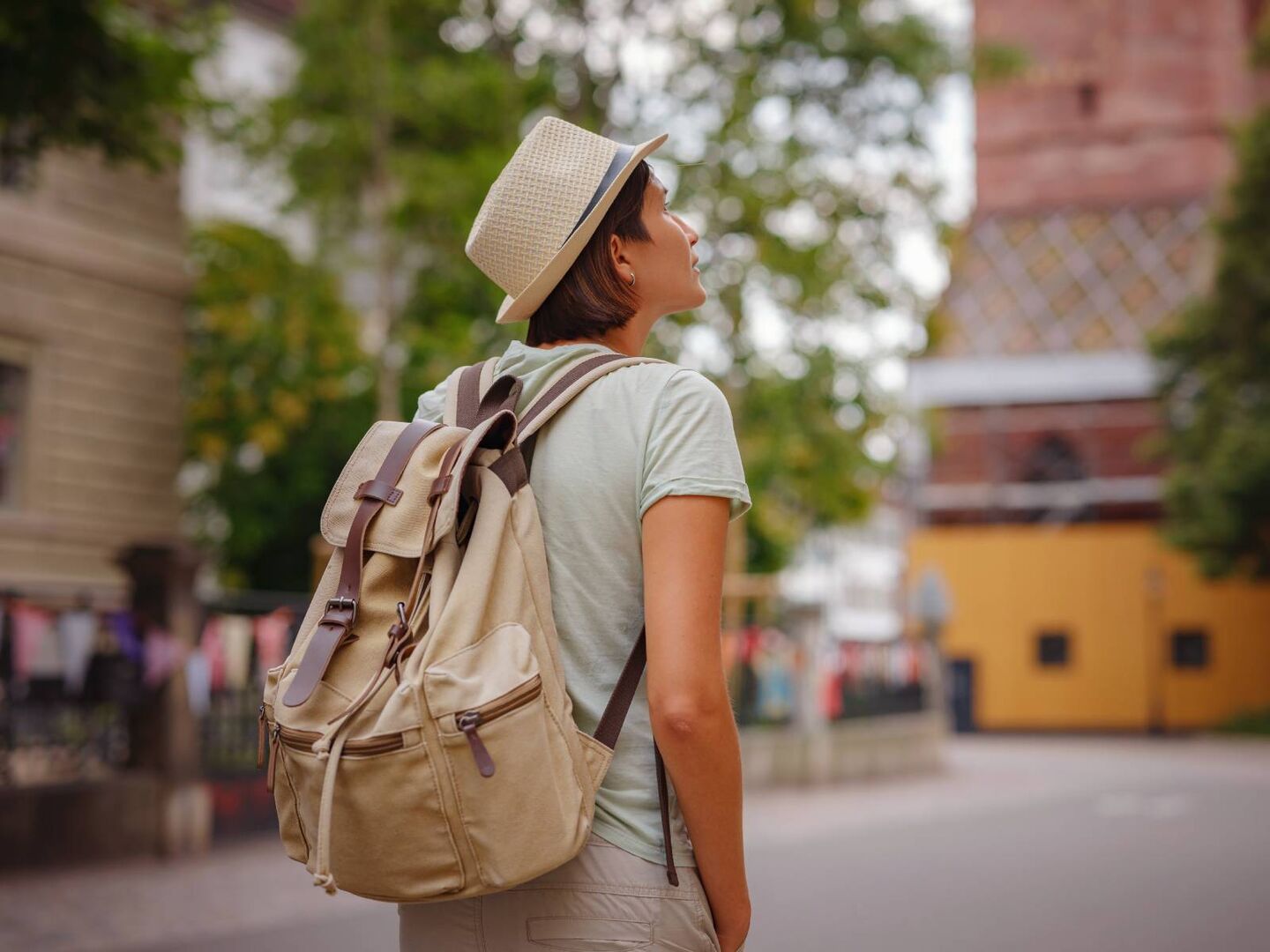 Eine junge Frau, hell gekleidet und mit einem Rucksack ausgestattet, besucht touristische Attraktionen und Sehenswürdigkeiten.