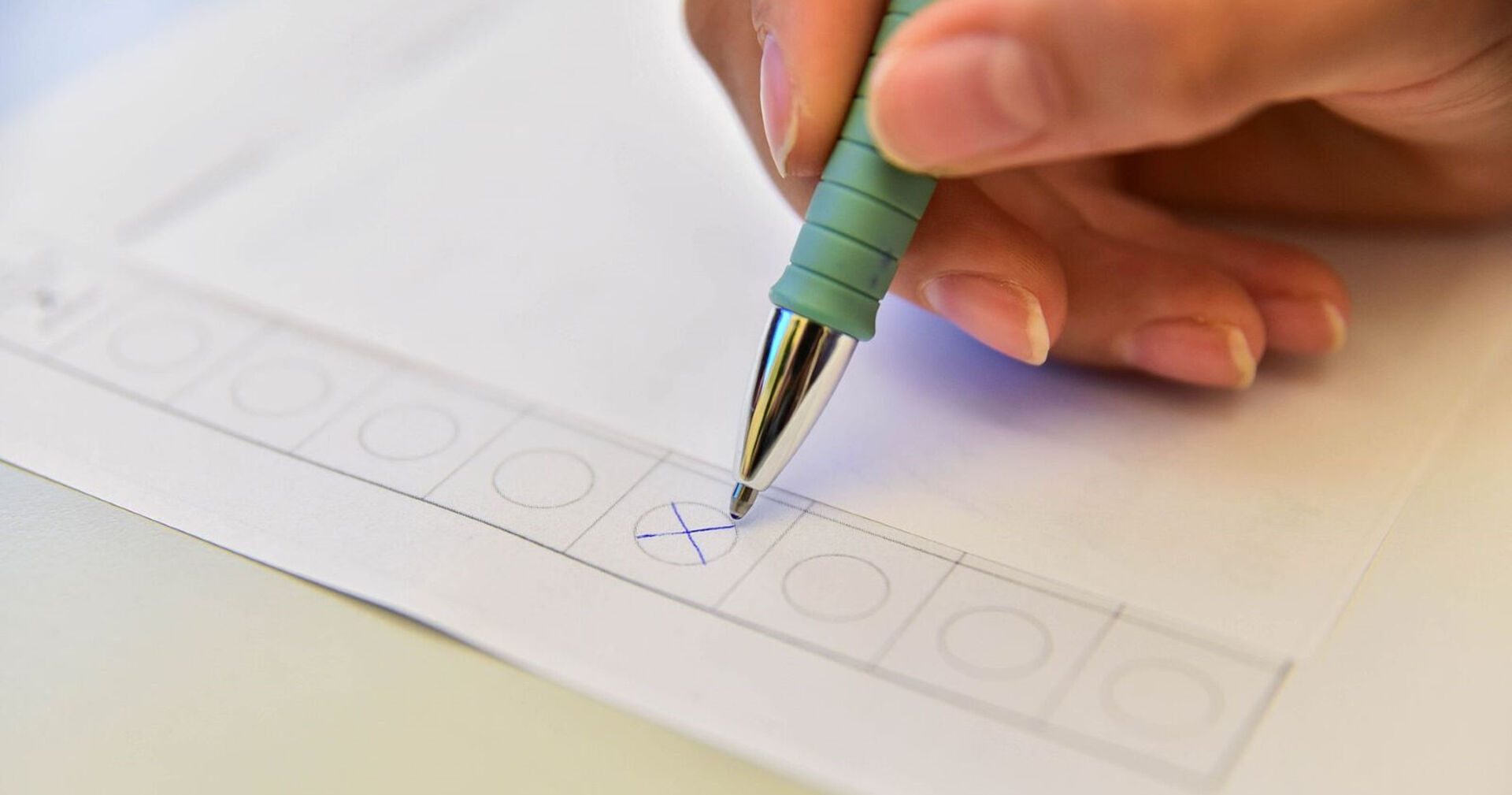 Eine Person gibt ihre Stimme bei einer Wahl ab und macht ein Kreuz.