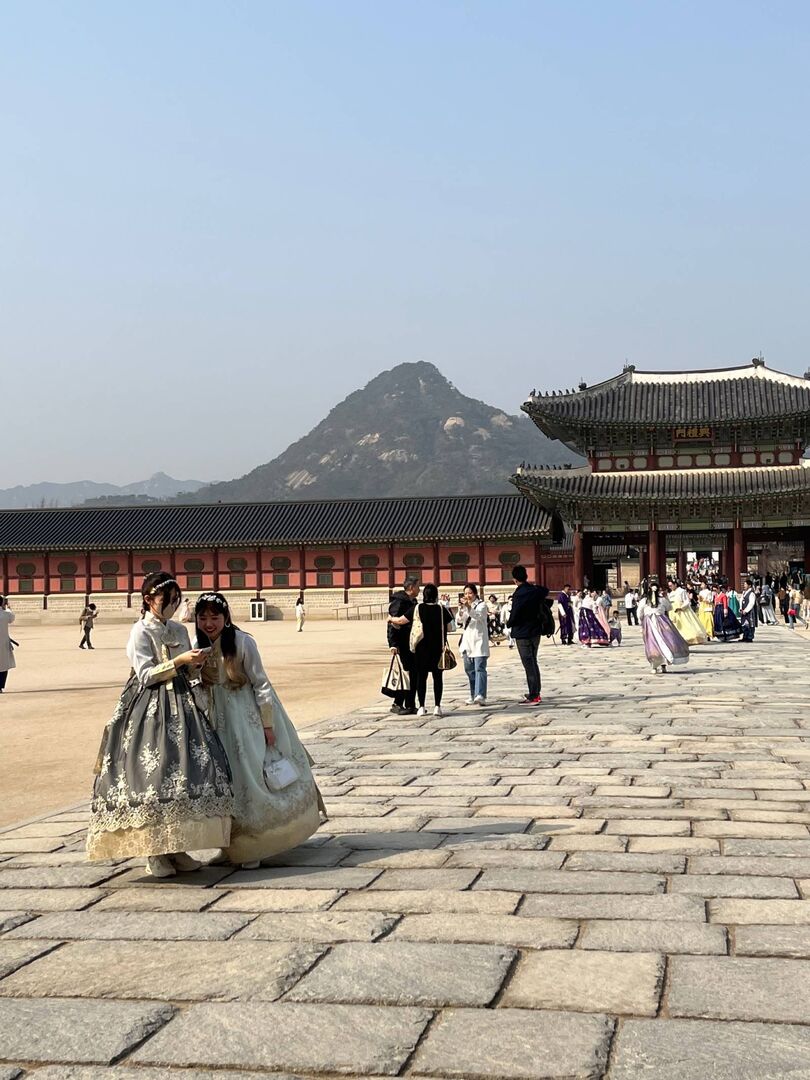 Unzählige, in traditionell koreanischer Tracht gekleidete Touristen schlendern über den Platz des Gyeongbokgung Palasts