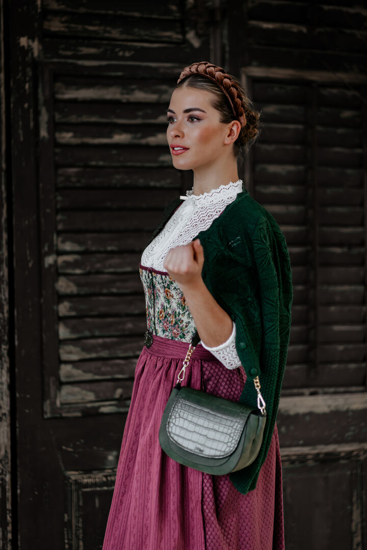 Model in modernem, beerenfarbigen Dirndl mit grüner Weste