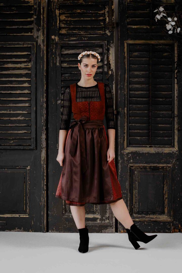 Model in brombeerfarbigem Dirndl mit schwarzer Bluse