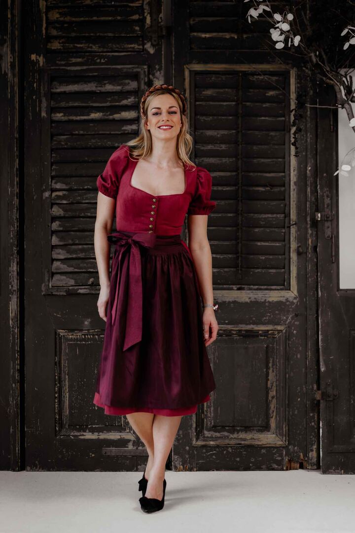 Model trägt brombeerfärbiges Dirndl mit Puffärmeln
