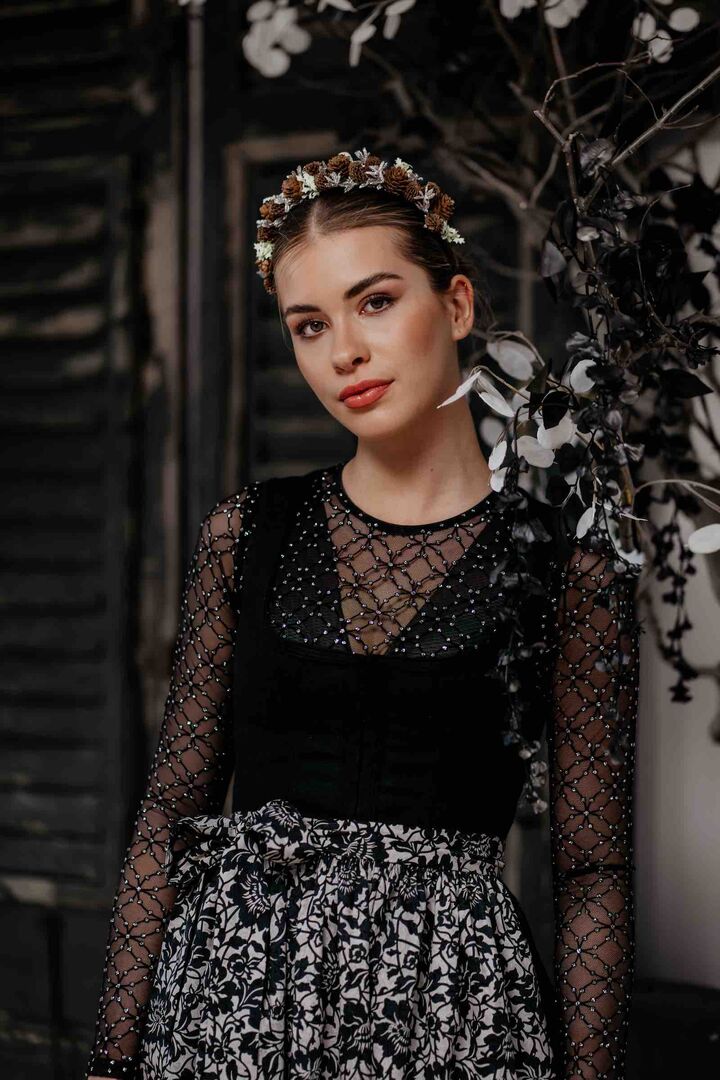 Model im schwarzen Dirndl mit schwarz-weißer Schürze