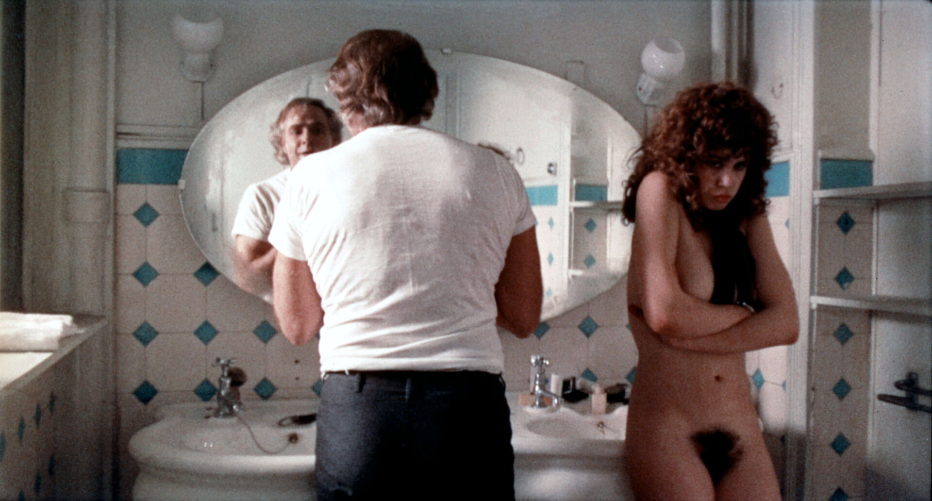 Eine Szene aus dem Film &quot;Der letzte Tango in Paris&quot;: Marlon Brando rasiert sich in einem Badezimmer im Spiegel, Maria Schneider steht nackt, mit verschränkten Armen neben ihm