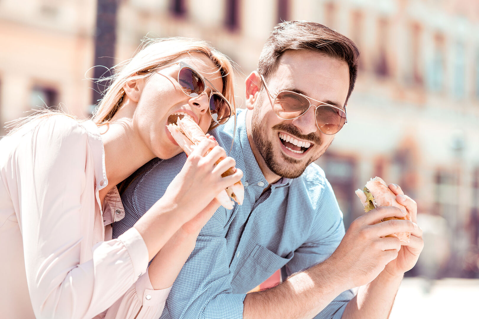 Frau und Mann sitzen in der sonne und genießen ein Sandwich