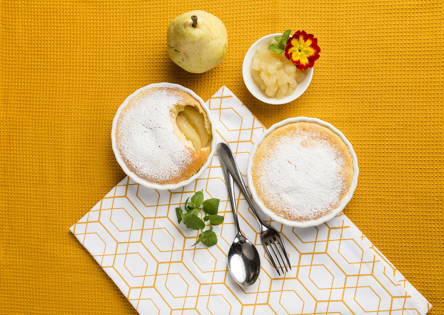 Zwei Schalen Birnen-Topfensouffle auf einer gelben Tischdecke