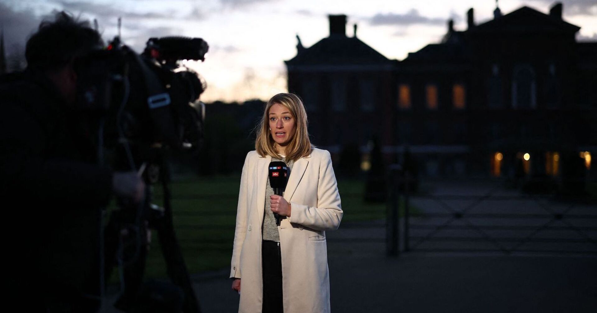 Dämmerung, Journalistin mit Mikro steht vor dem Palast
