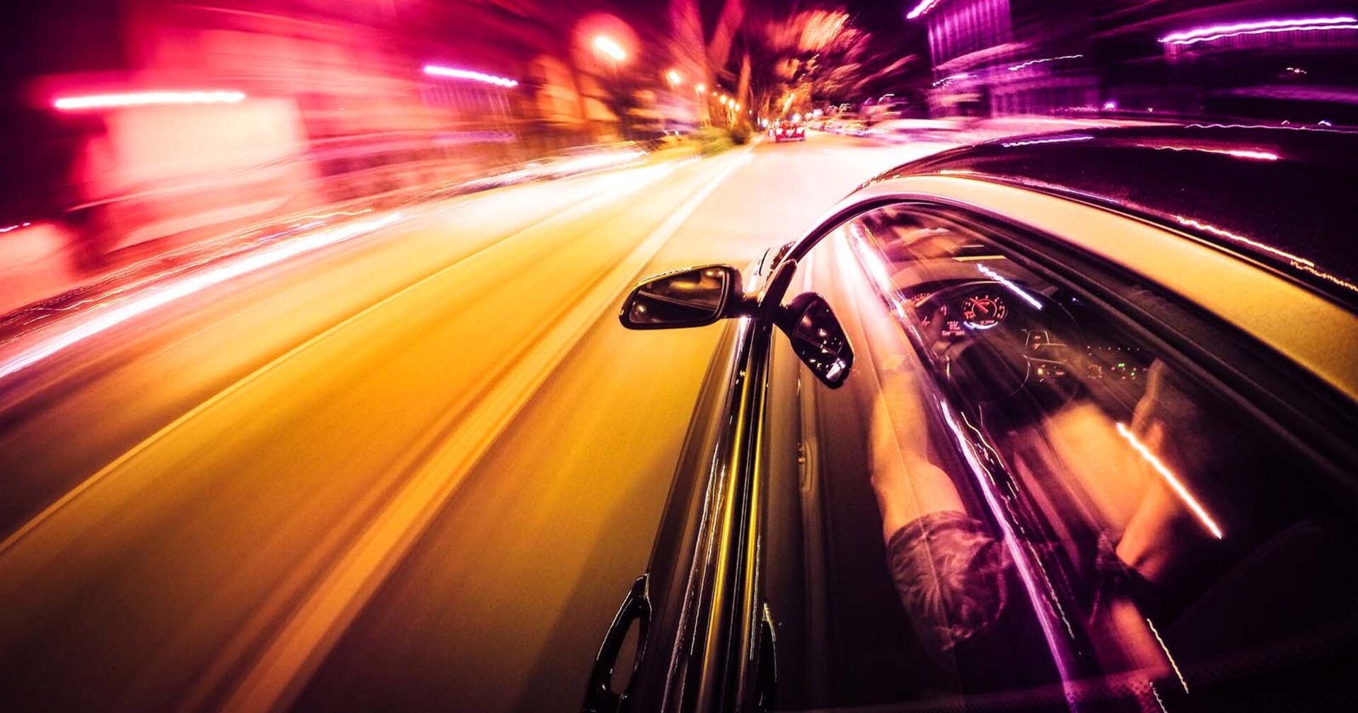 Ein Auto fährt mit hoher Geschwindigkeit in der Nacht durch eine Stadt