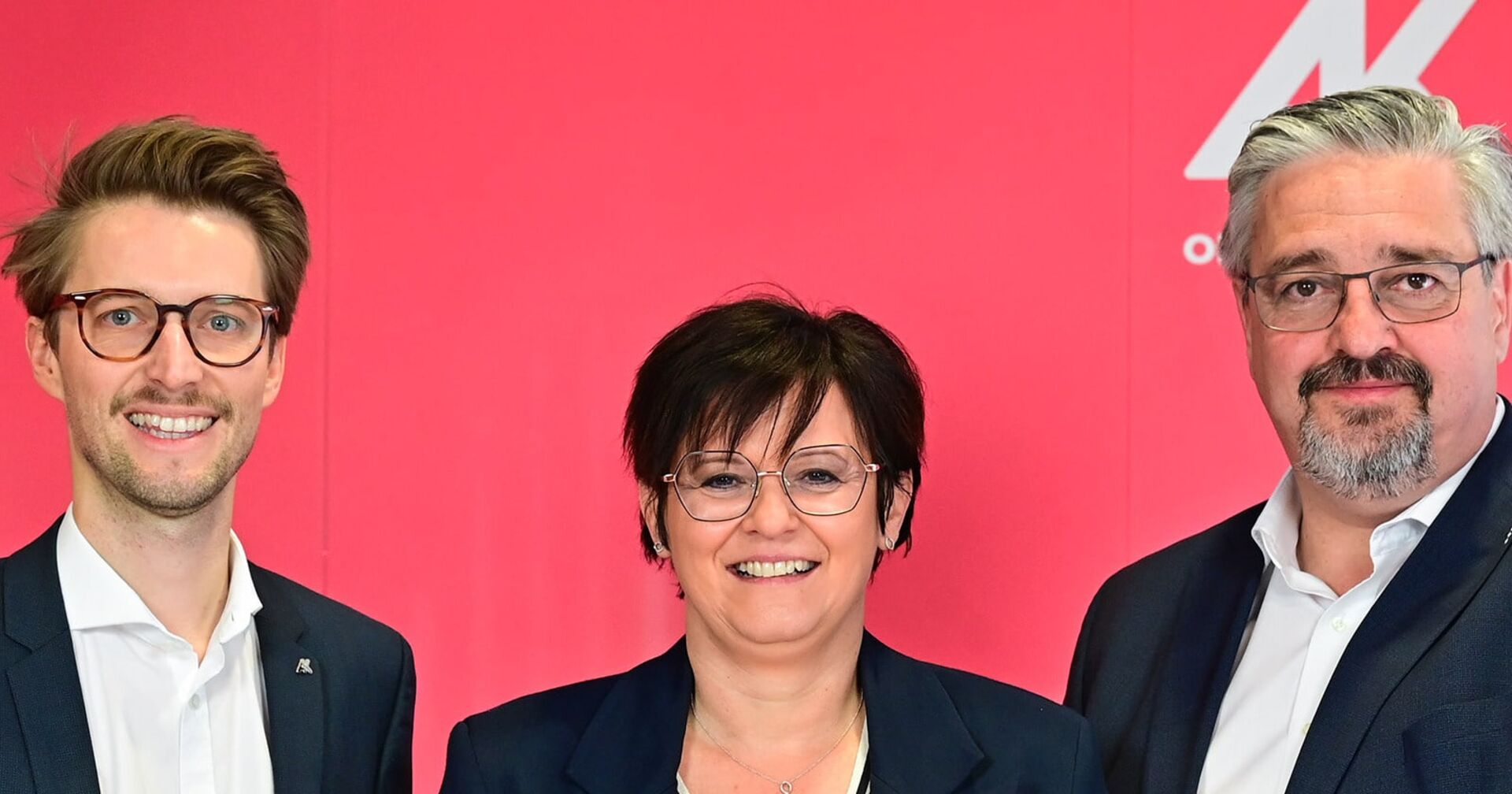 In der Mitte lacht eine Dame mit kurzen braunen Haaren. Ebenfalls lachend: Die Herren links und rechts von ihr, die beiden einen kurzen Vollbart haben und eine Brille tragen. Zu sehen sind links: Gerhard Bremm (Wahlleiter), Andrea Heimberger (AK-Direktorin) und Andreas Stangl (AK-Präsident)-