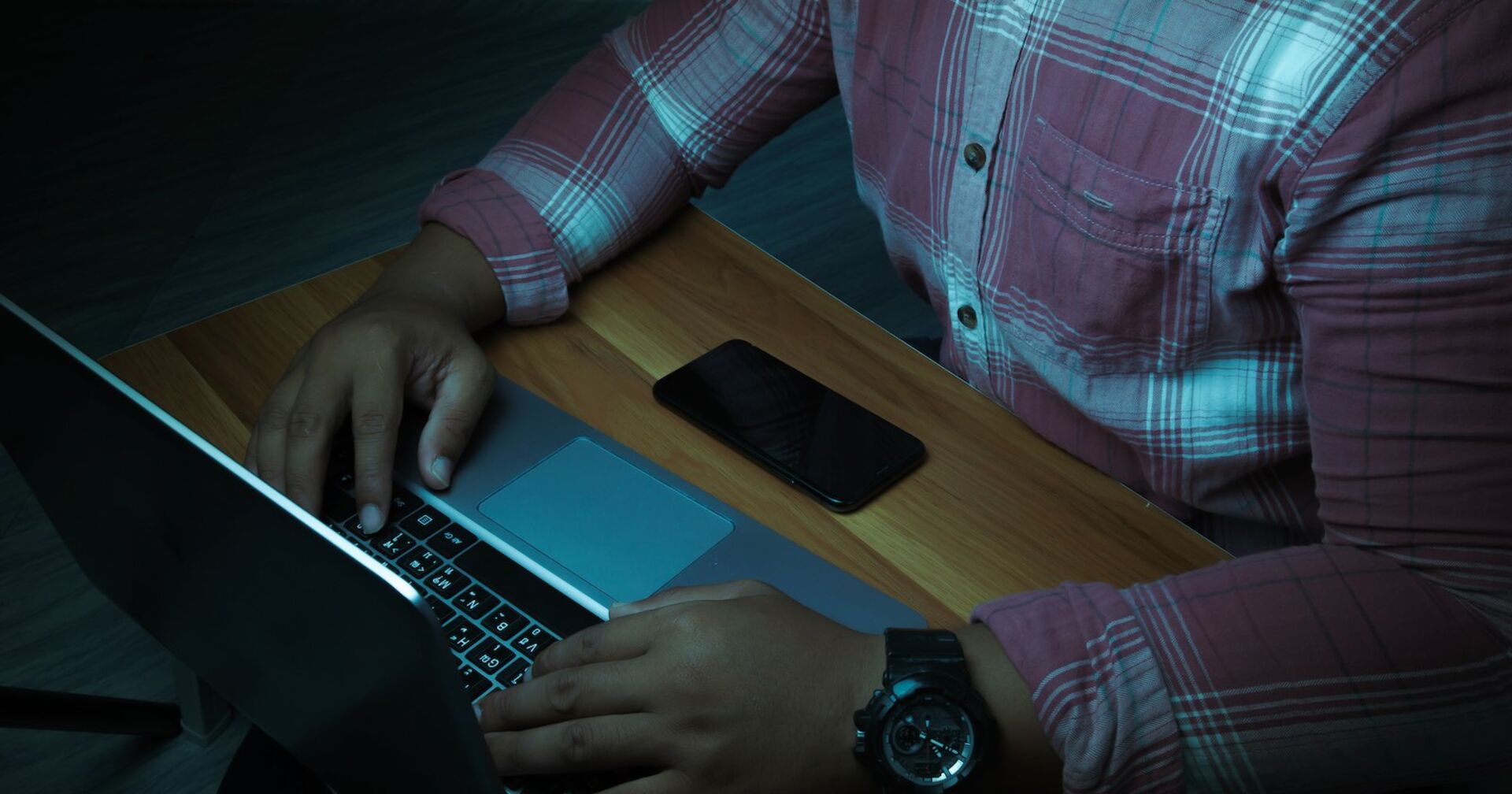 Ein Mann sitzt im Dunkeln vor einem Laptop.