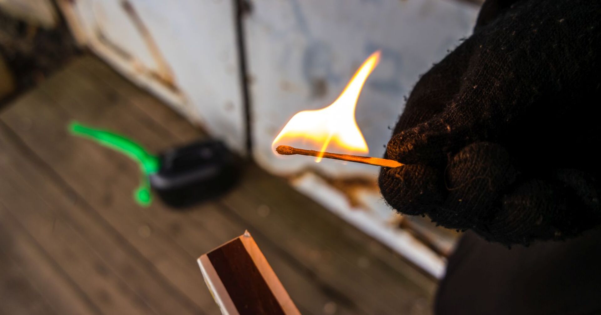 Jemand legt mit einen Zündholz einen Brand.
