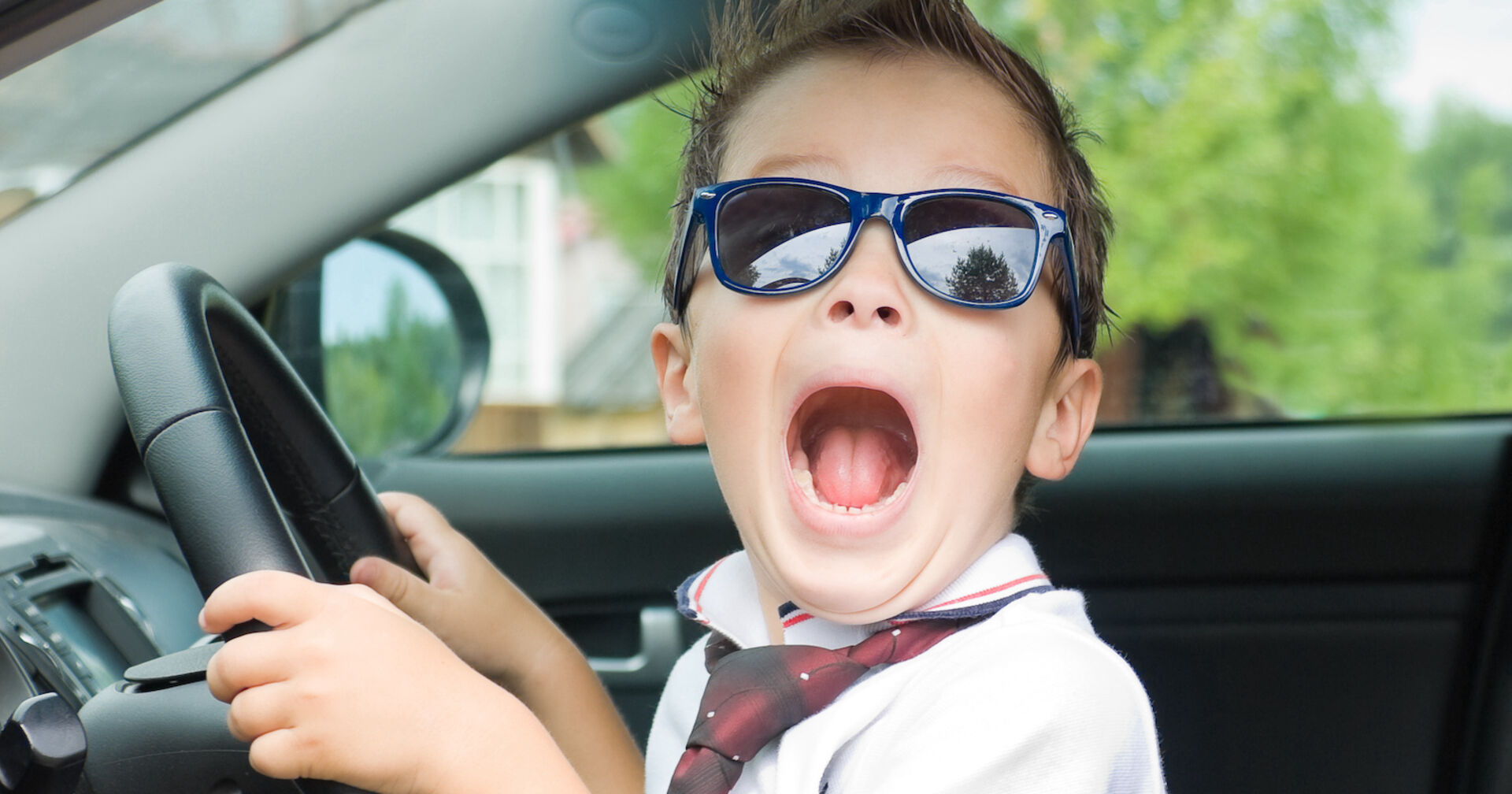 Bub sitzt am Steuer eines Autos