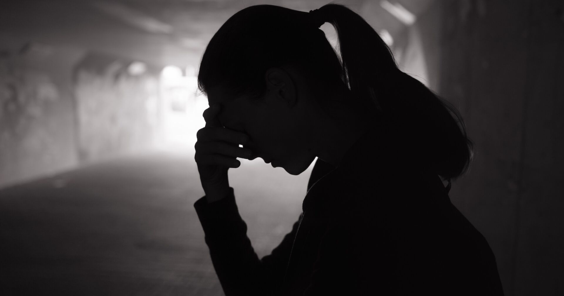 Ein Mädchen traurig in einer dunklen Unterführung.