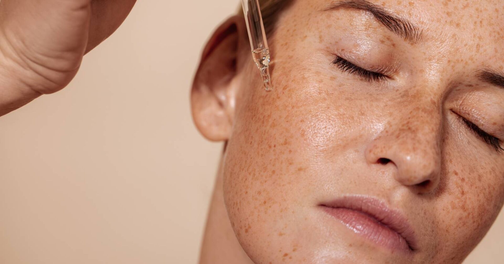 Junge Frau beim Auftragen eines Serums aus einer Ampulle auf die Haut