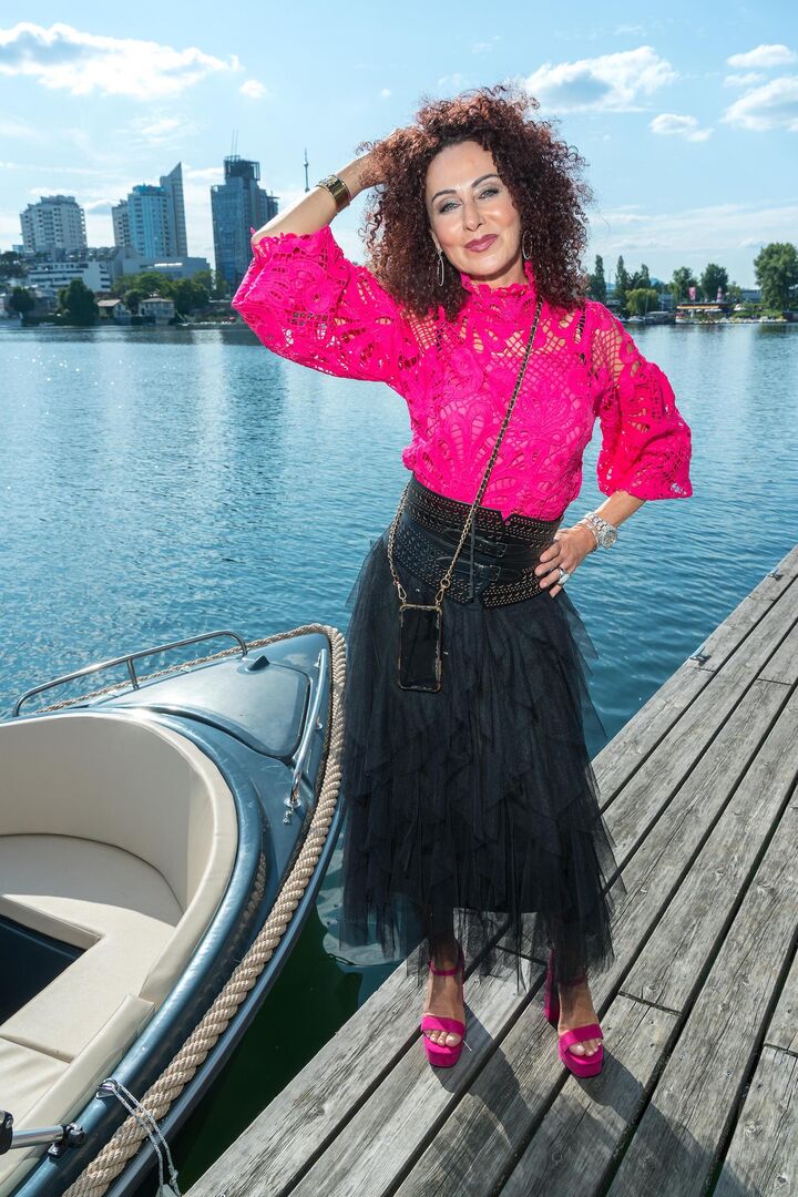 Christina Lugner. mit einem pinken Pullover und einem langen, schwarzen Rock.