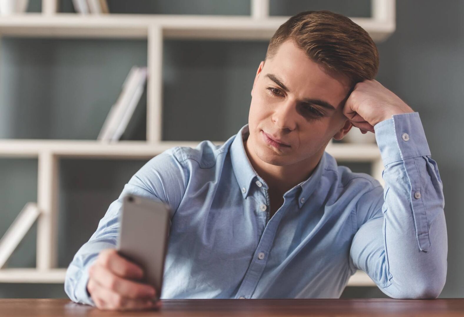 Ein Mann sitzt enttäuscht vor seinem Smartphone.