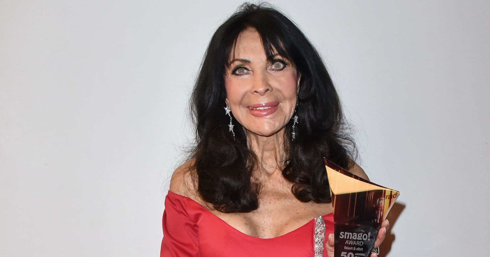 Dunja Rajter mit einem roten Kleid und offenen schwarzen Haaren.