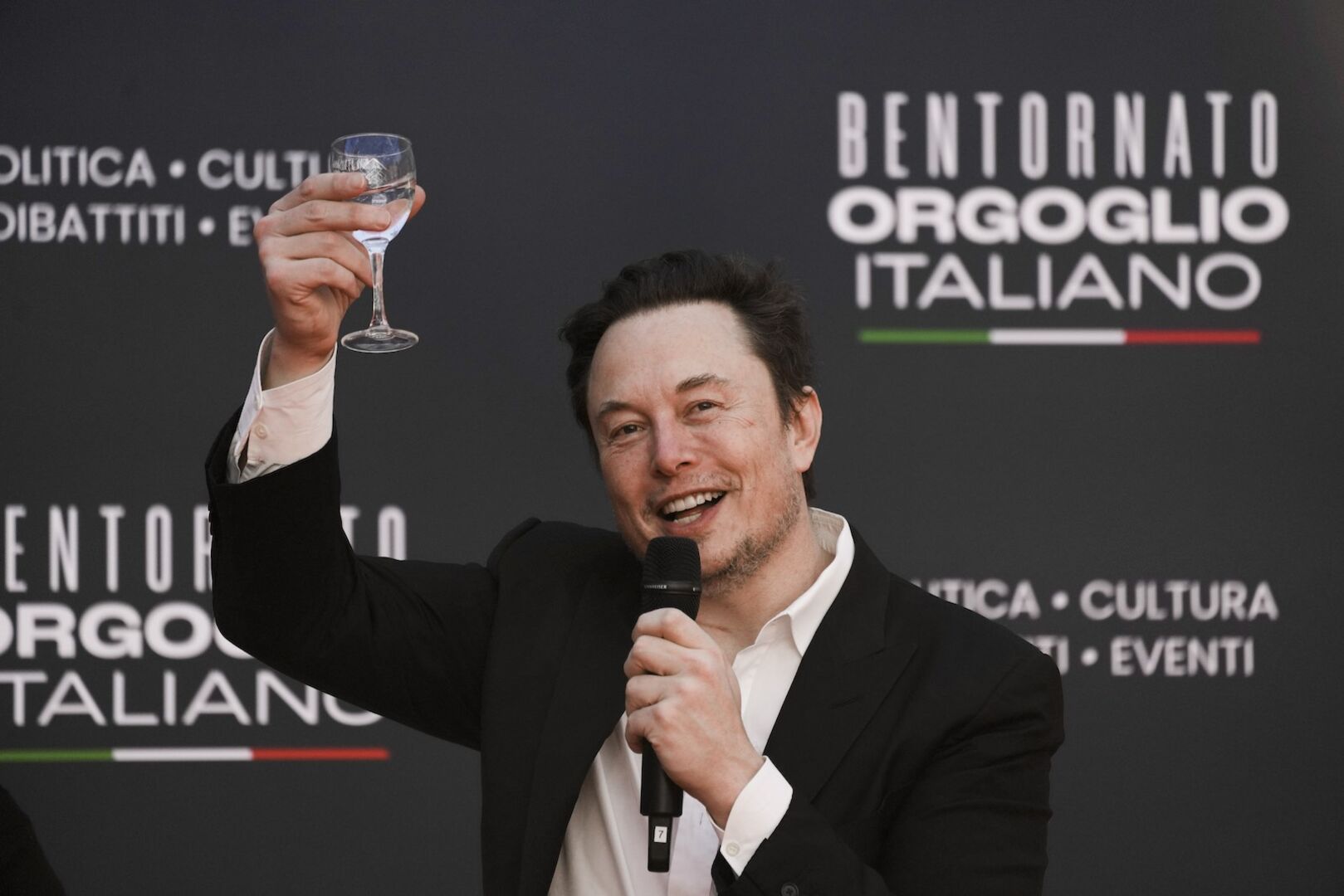 Elon Musk hebt ein Glas zum Anstoßen.