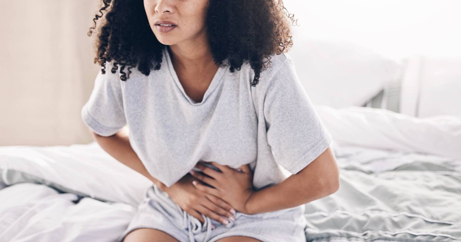 Frau, die sich vor Menstruationsbeschwerden den Bauch stützt