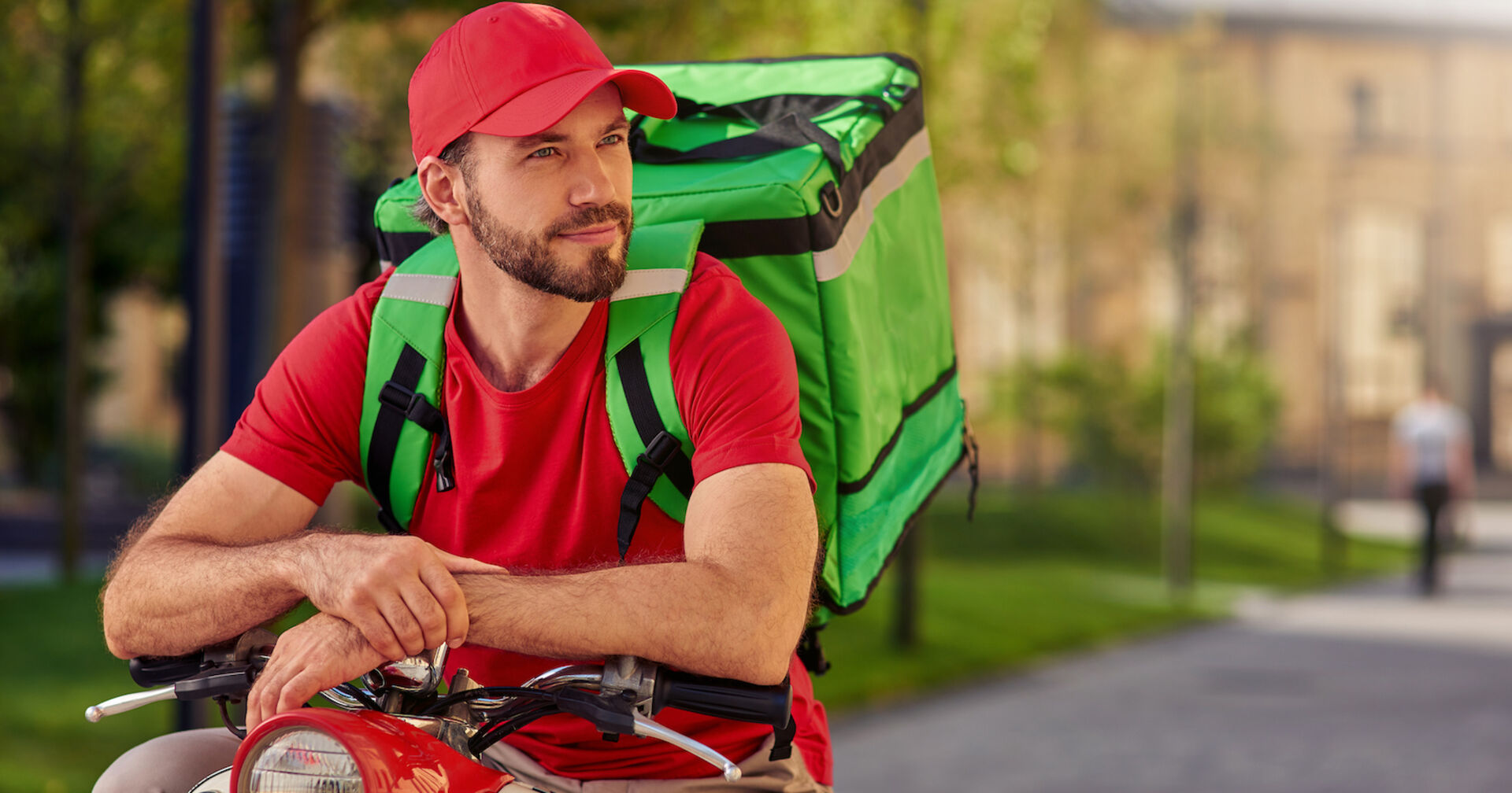 Essenslieferant am Roller mit rotem T-Shirt und roter Kappe