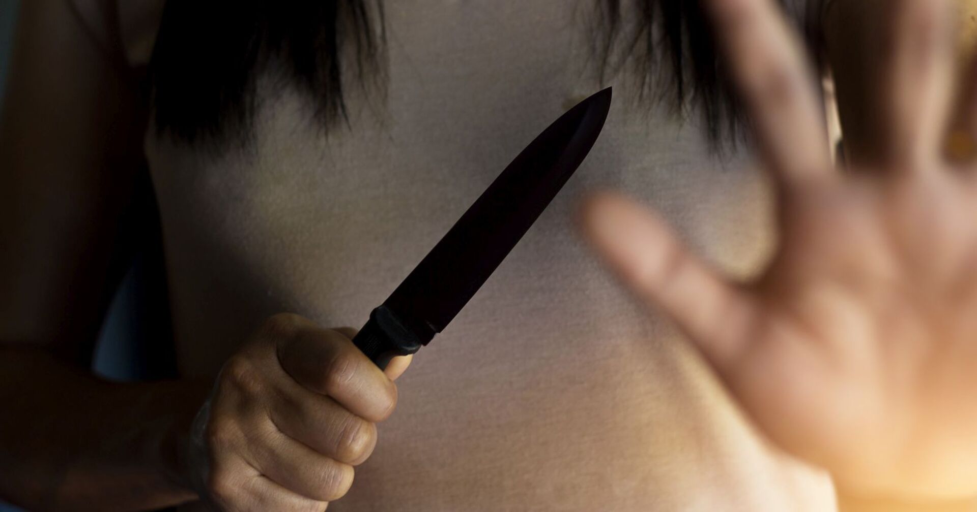 Eine Frau wehrt sich mit einem Messer.