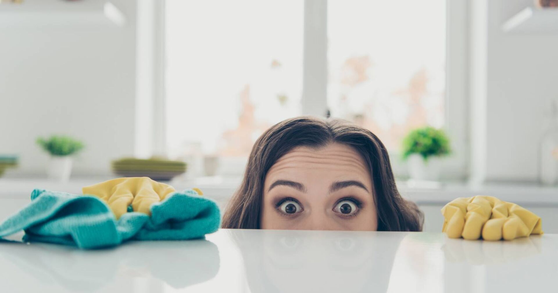 Frau, die über den Küchentresen lugt. Es ist ihr Kopf zur Hälfte zu sehen.