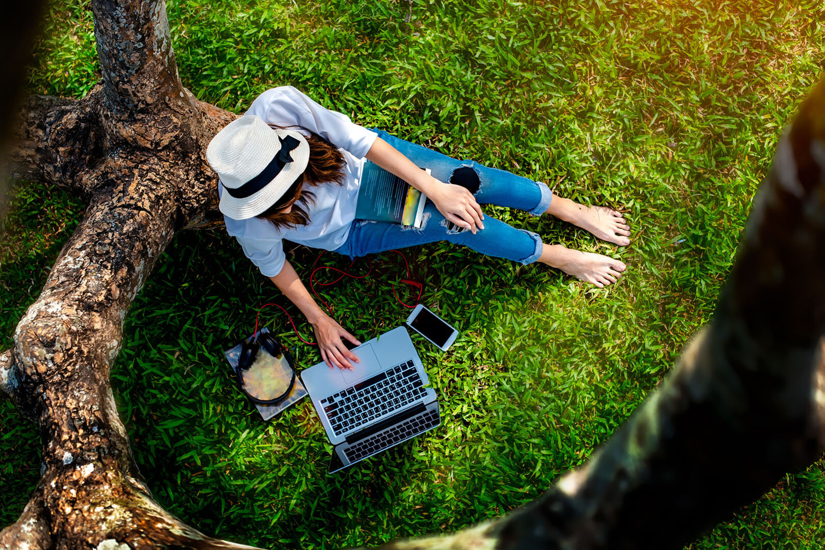 Frau sitzt mit Laptop im Garten | Credit: iStock.com/Iam Anupong